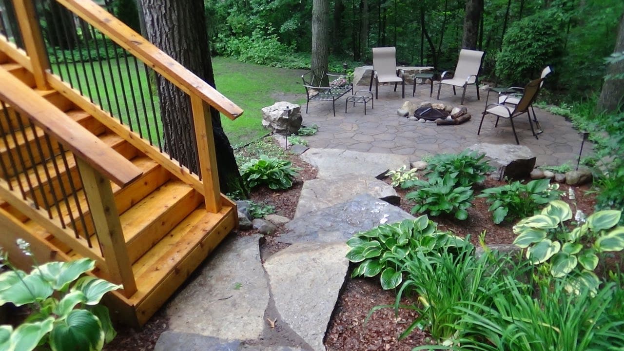A deck staircase leads to landscaping in a backyard. For deck builders in Ada MI, trust Precision Decks & Sunrooms