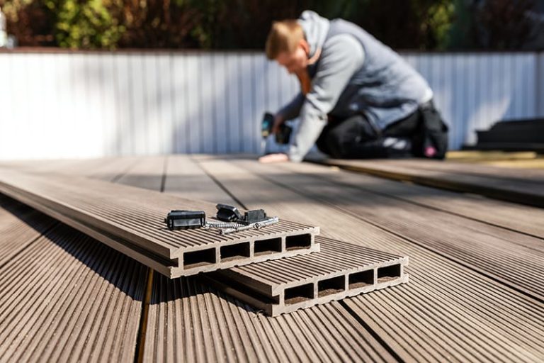 A deck installer uses an cordless drill to install composite decking.What is better composite or wood decking? For large projects, wood. Samll to medium, all weather areas, composite.