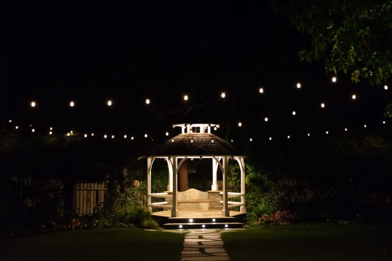 Patio lighting ideas take many forms, including (as shown) string lights around a Gazebo at night, or lights within the steps of a walkway.