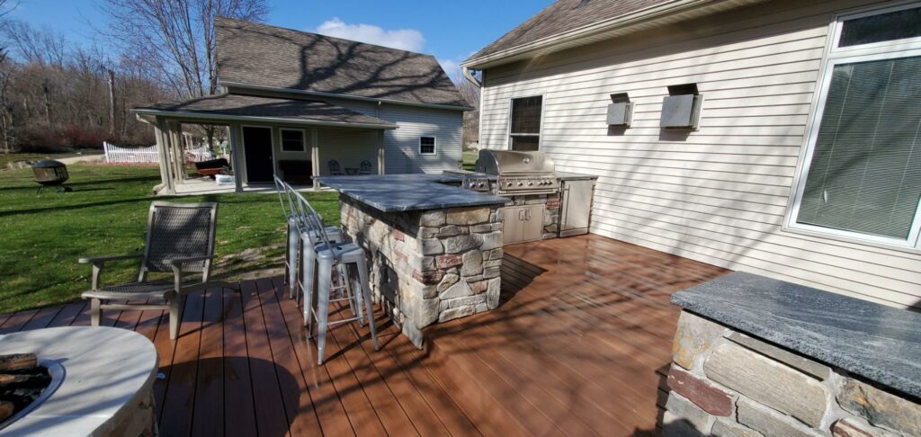Photo of an outdoor kitchen with grill, countertop, and seating area.