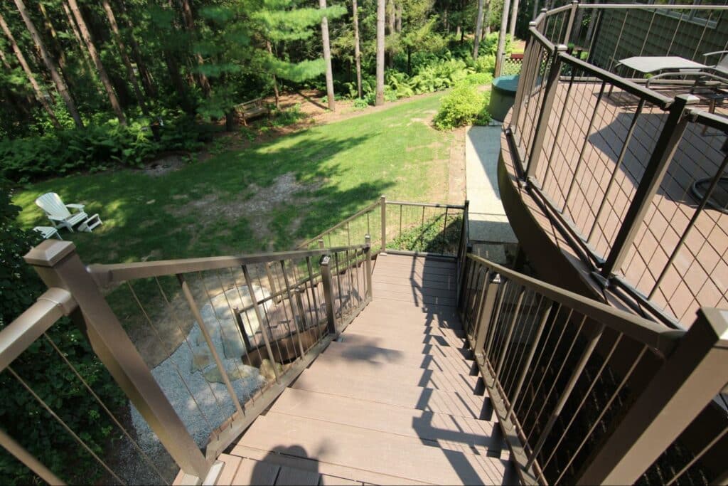Photo of a TimberTech Advanced PVC Deck by AZEK showing an elevated, curved deck and stairs leading down to the ground.