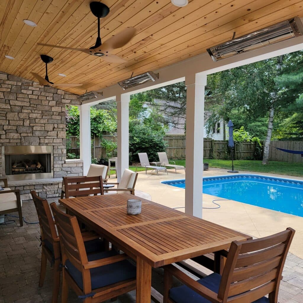 Photo of a covered patio with brick pavers with a dining table and chairs and a pool.