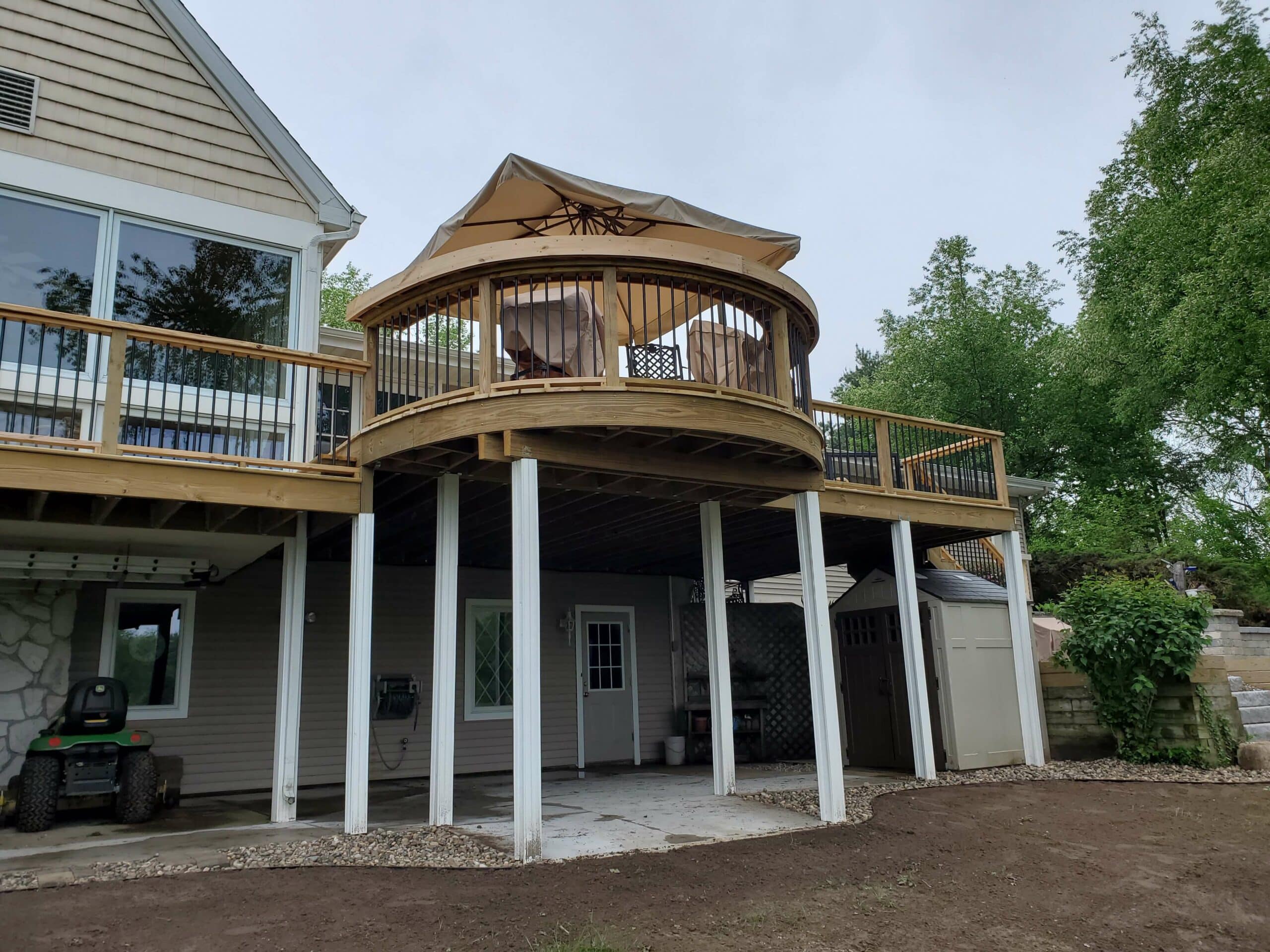 Photo of an elevated curved deck made of wood with an underdecking area for additional storage. Curved deck builder, grand rapids michigan