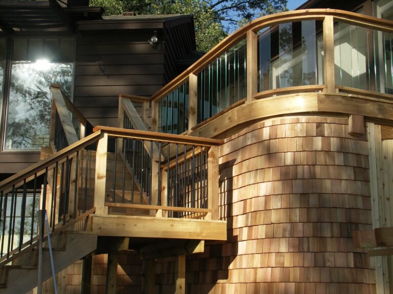 Photo of a wood deck with wooden railings and wood siding on home.