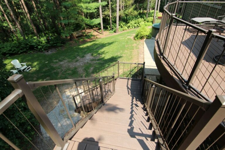 Photo of an elevated curved deck with deck railing and steps.