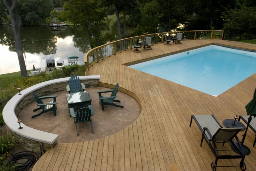 Photo of a curved pool deck with a paver patio area and sitting wall.
