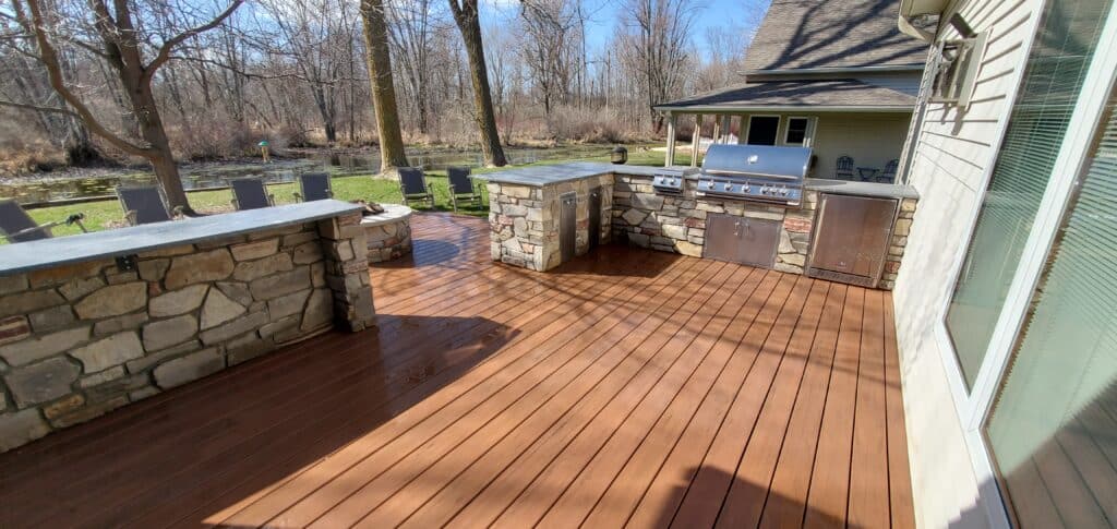 Photo of a composite deck with an outdoor kitchen and stone walls.