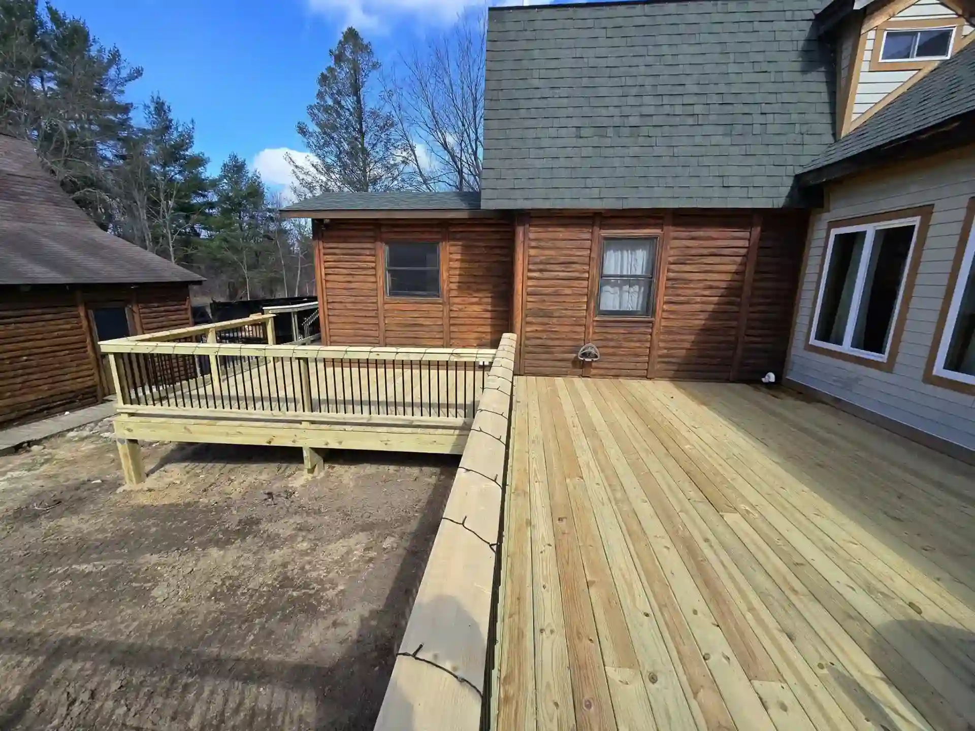 a wood deck with wood rails and black metal balusters