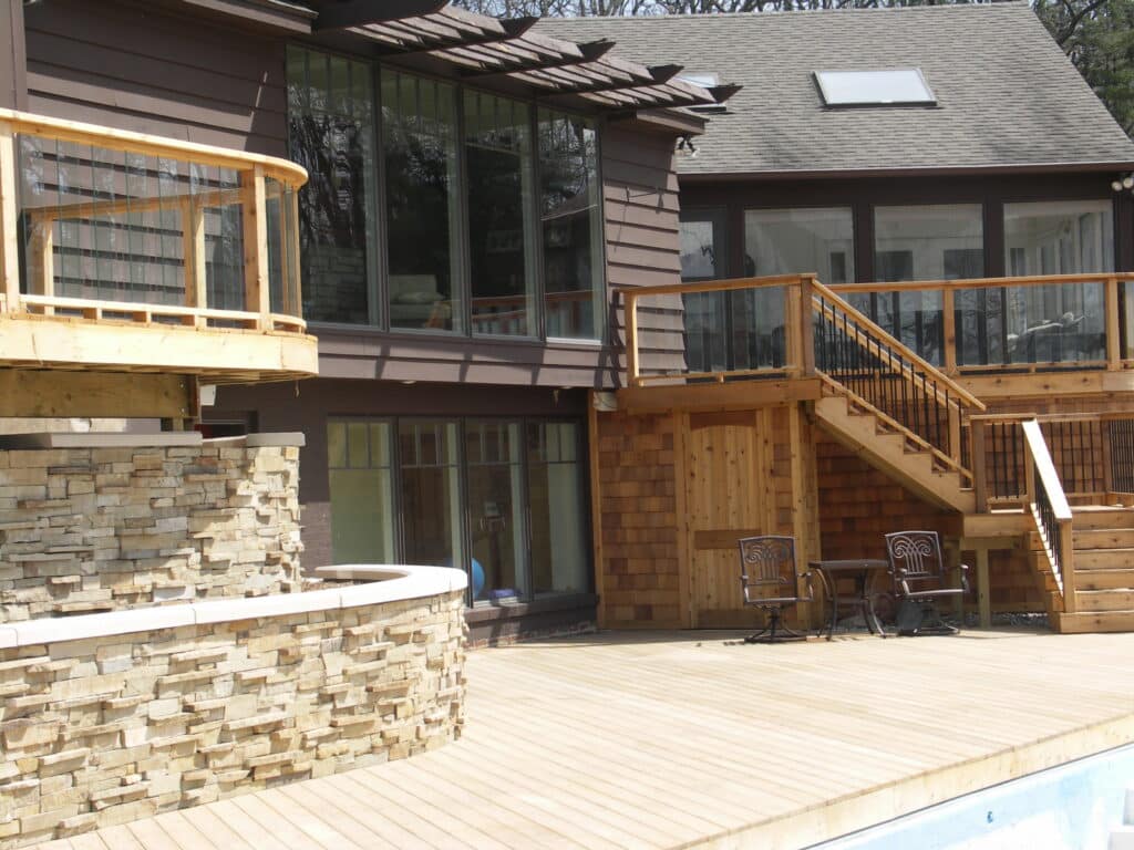 luxury deck ideas - home with two wooden decks, plus a wooden pool deck, plus glass panels - Deck Builder in Greater Gand Rapids Area