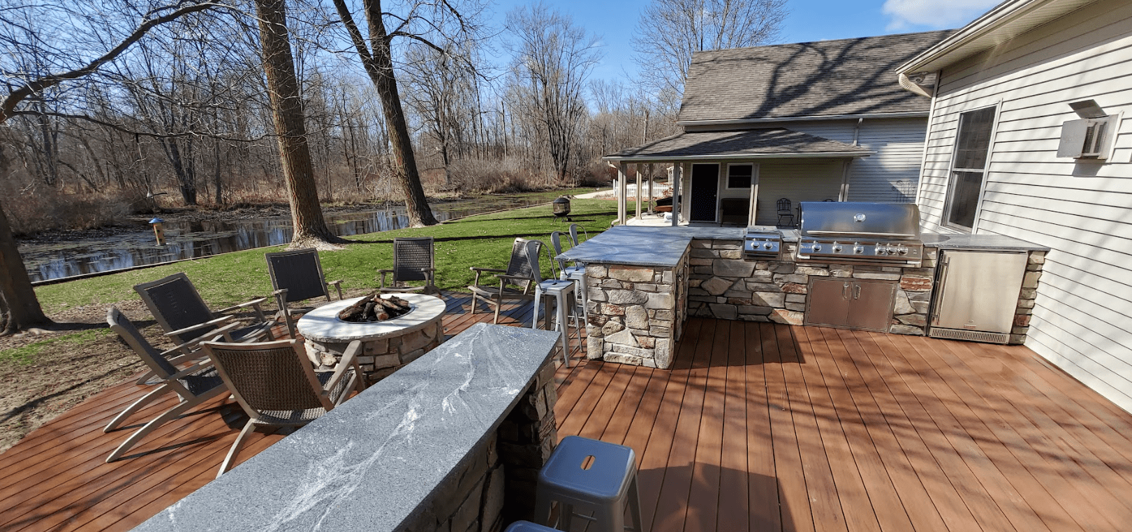 photo of a fire pit on a deck with seating and outdoor kitchen