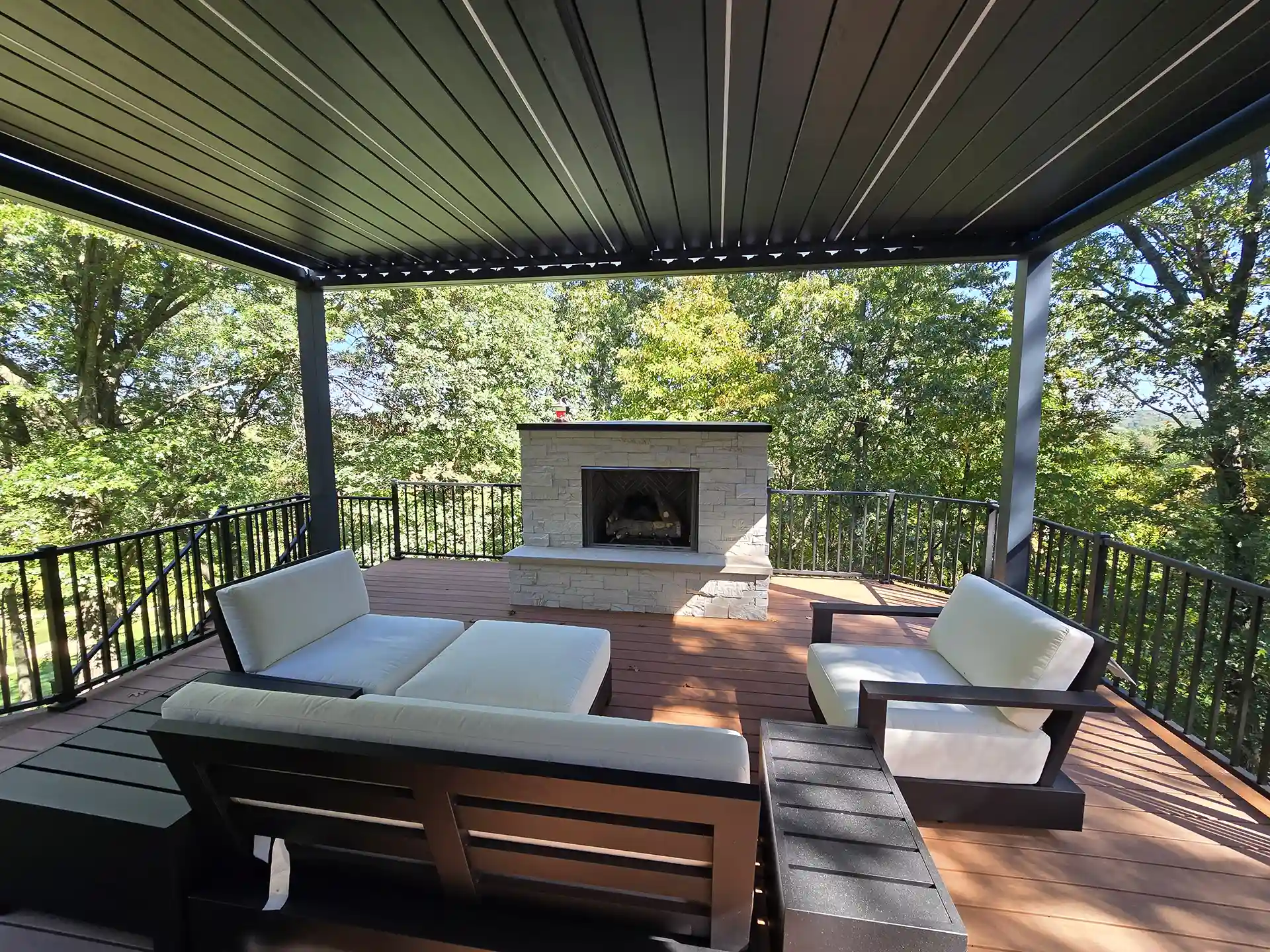 photo of elevated deck with outdoor fireplace, outdoor furniture, louvered roof, and deck railing 