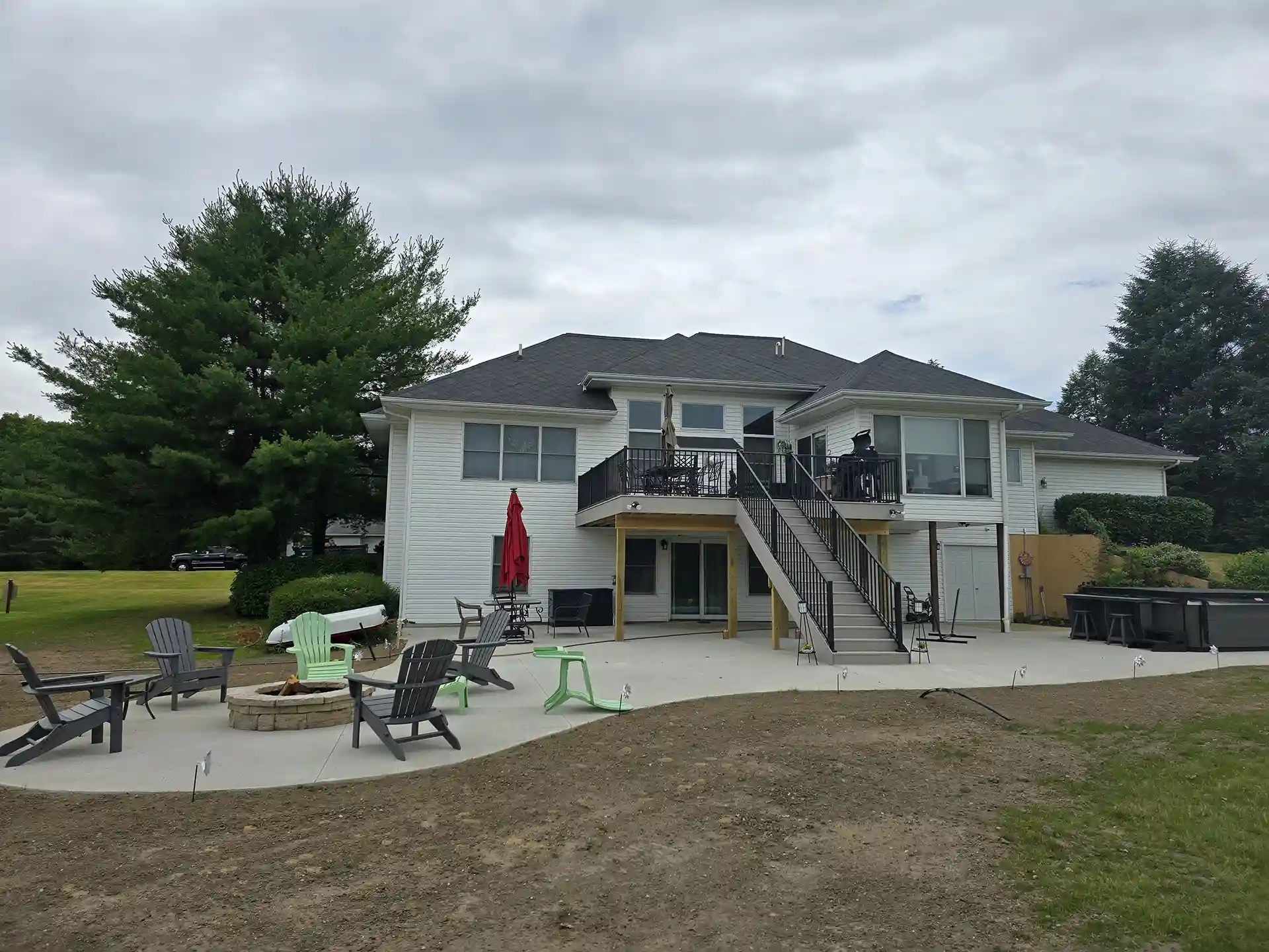 photo of elevated deck with concrete patio and outdoor fire feature and hot tub