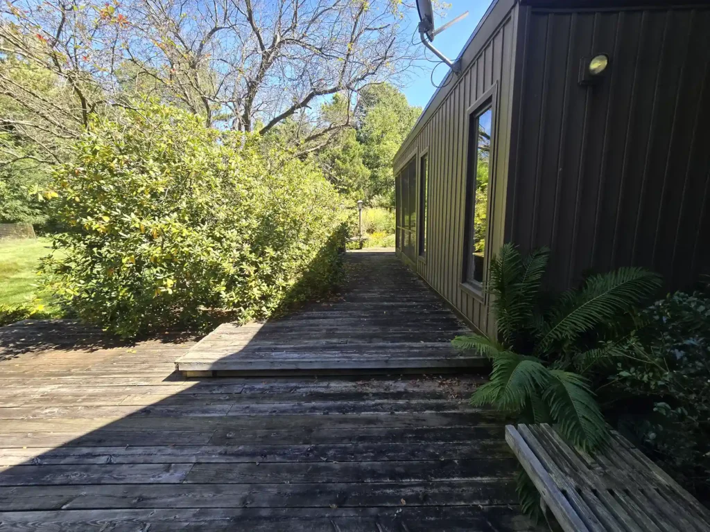 Worn-out wooden deck with uneven steps and faded boards.