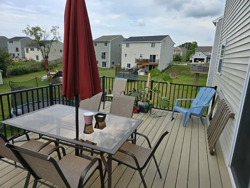 Outdoor dining set on a spacious AZEK deck with black railings.