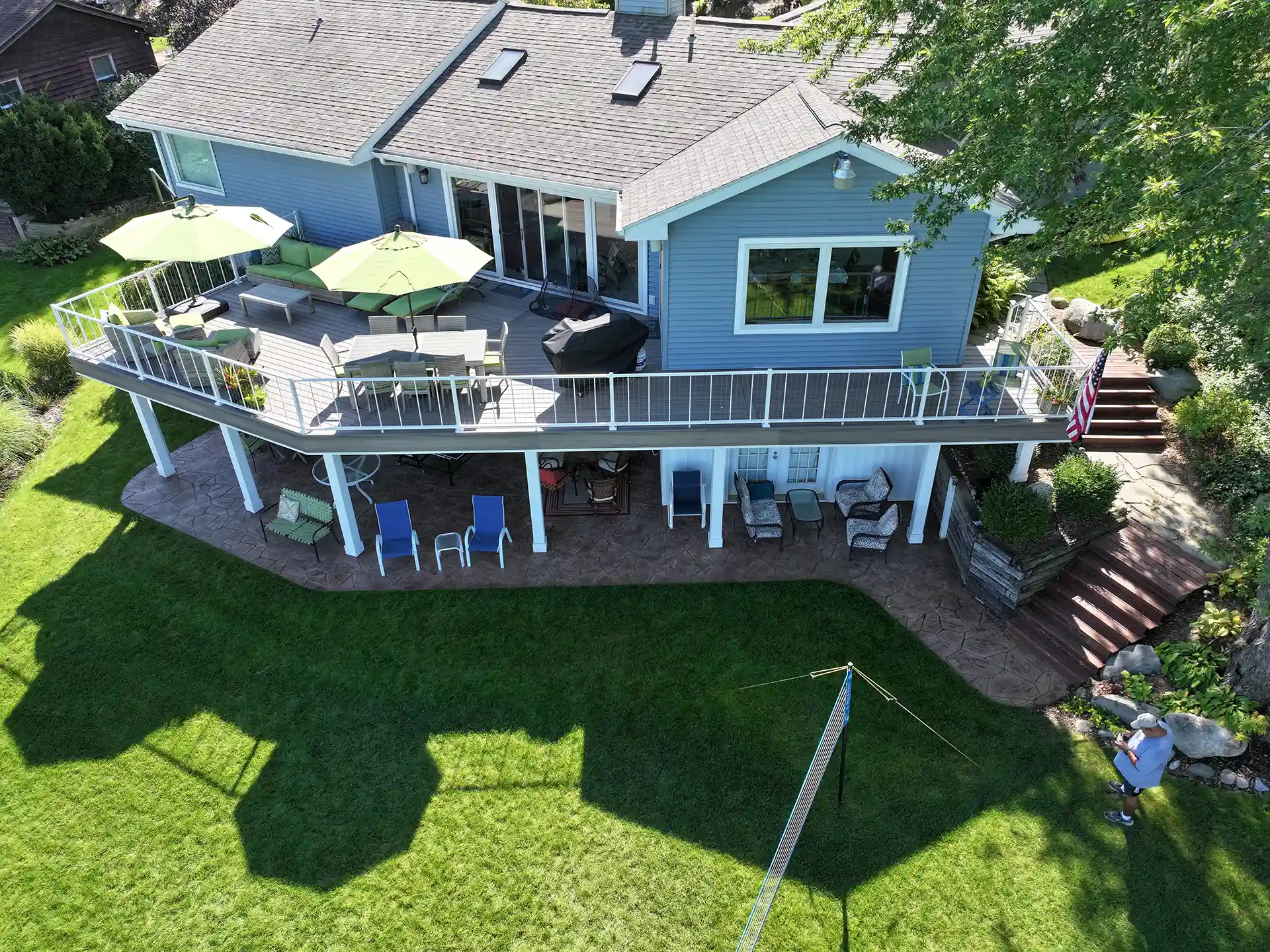 Photo of an elevated deck with patio below. Deck uses umbrellas as a way to explore how to keep a deck cool in summer.
