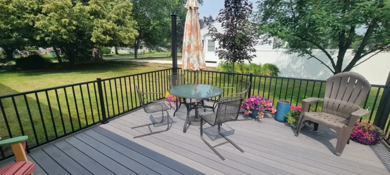 PHoto of a gray composite deck with outdoor furniture and black metal railing
