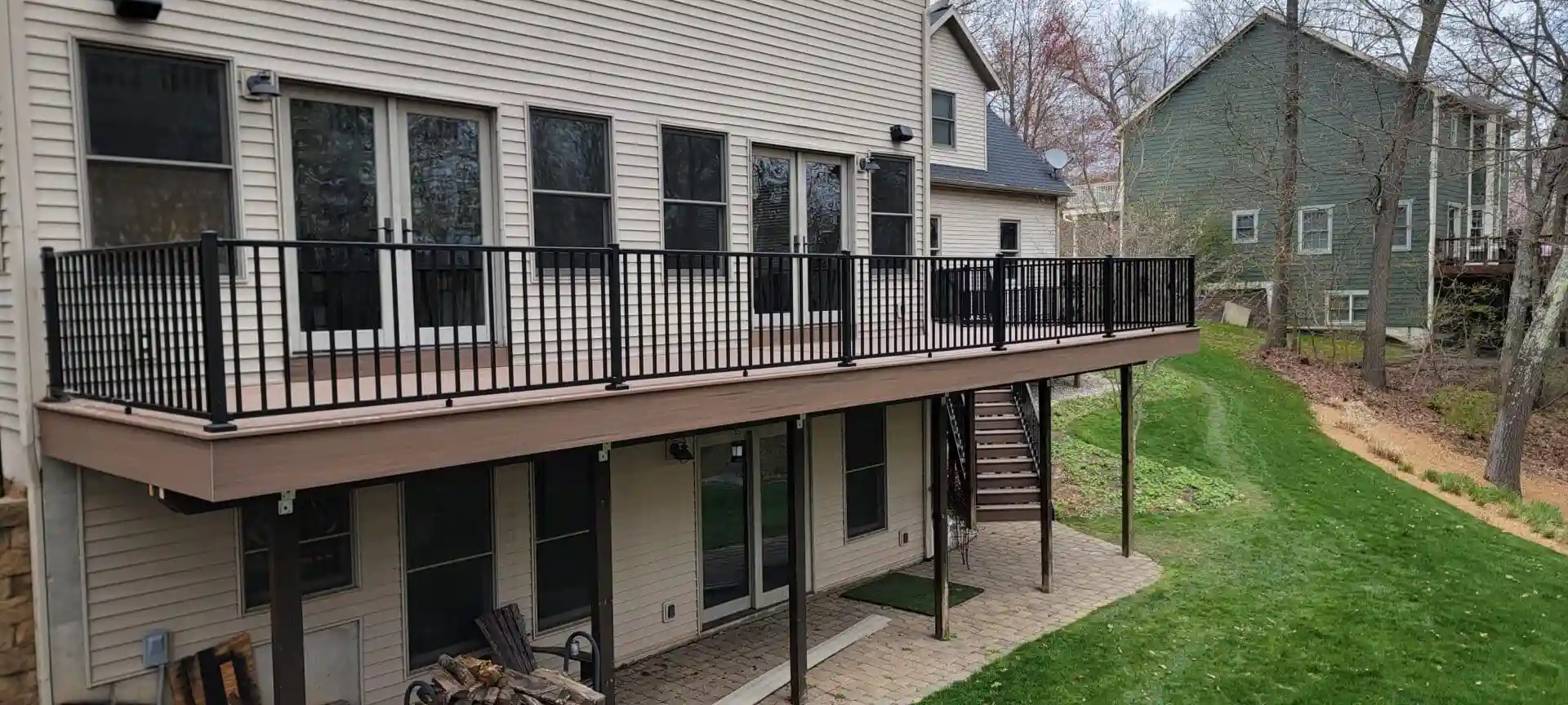 Photo of spacious elevated deck with black metal railings and wide staircase leading to yard.