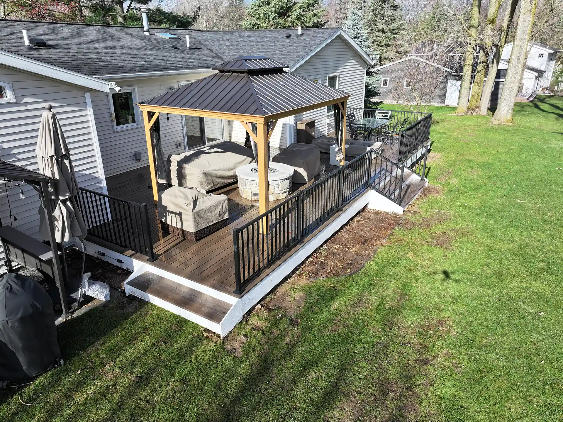 PHoto of a low-maintenance deck with a pavilion-style structure, fire pit and outdoor furniture