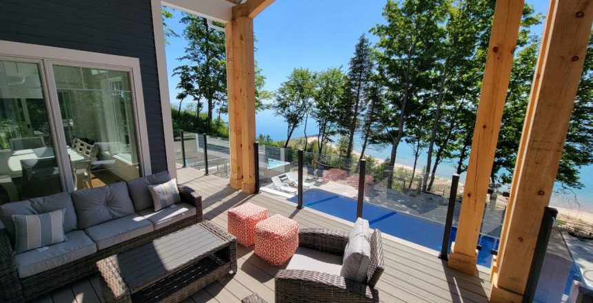 A unqie patio design overlooking a pool along a lakeshore house.